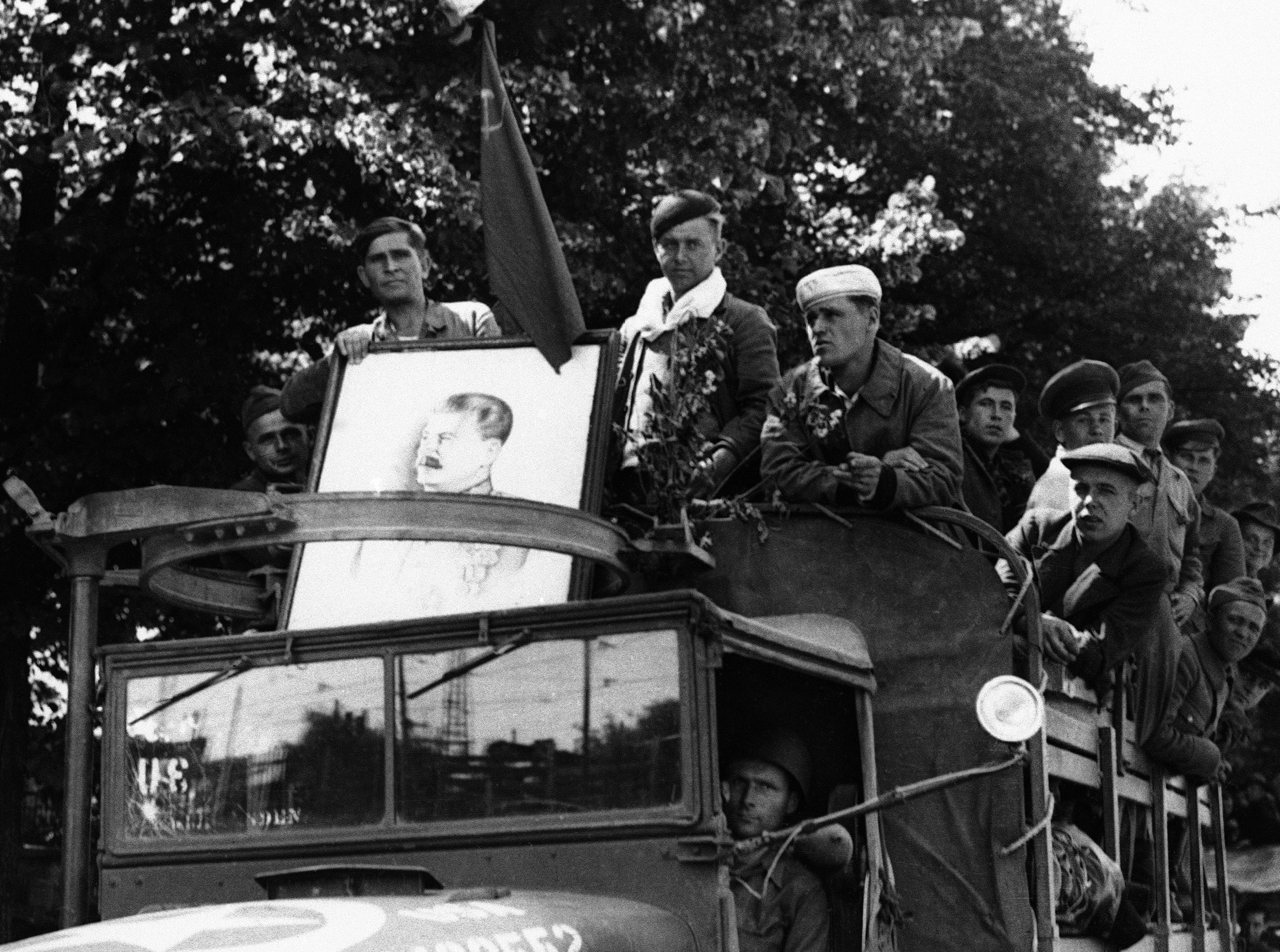 Εκτοπισμένοι Σοβιετικοί, πολλοί από τους οποίους αναγκάστηκαν να εργαστούν σε ναζιστικές συμμορίες σκλαβιάς είναι σκαρφαλωμένοι σε ένα αμερικανικό φορτηγό στο Μόναχο της Γερμανίας στις 21 Ιουνίου 1945, στο πρώτο στάδιο του ταξιδιού τους στο σπίτι. Στο μπροστινό μέρος του φορτηγού φαίνεται ένα πορτρέτο του στρατάρχη Στάλιν  (AP)